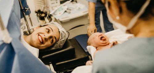 mother smiling looking at newborn baby