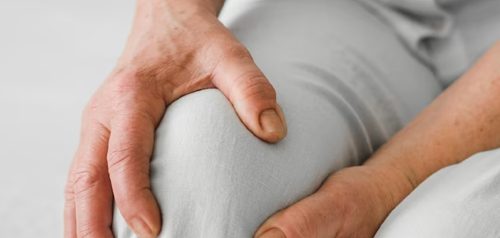 An elderly person holding their knee due to joint paint at The Quay Family Healthcare